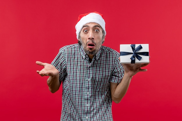 Vista frontal de um jovem segurando o presente de Natal no vermelho