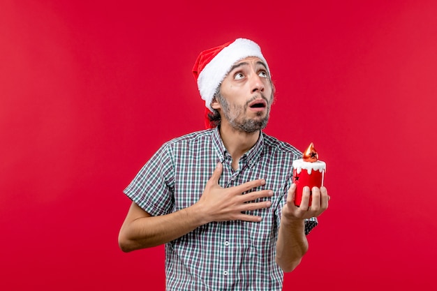Vista frontal de um jovem segurando um brinquedinho vermelho
