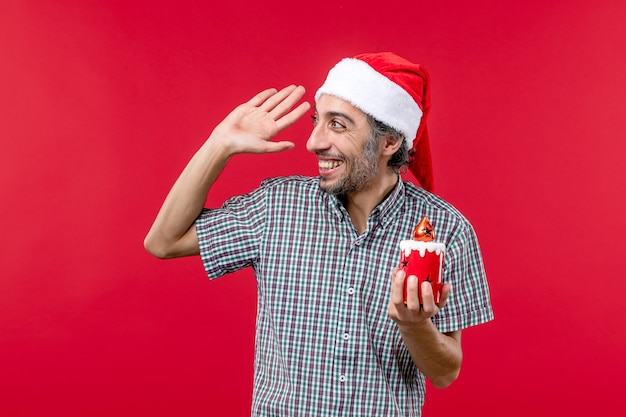 Vista frontal de um jovem segurando um brinquedo de Natal no vermelho