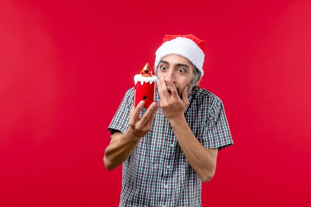 Vista frontal de um jovem segurando um brinquedo de Natal no vermelho