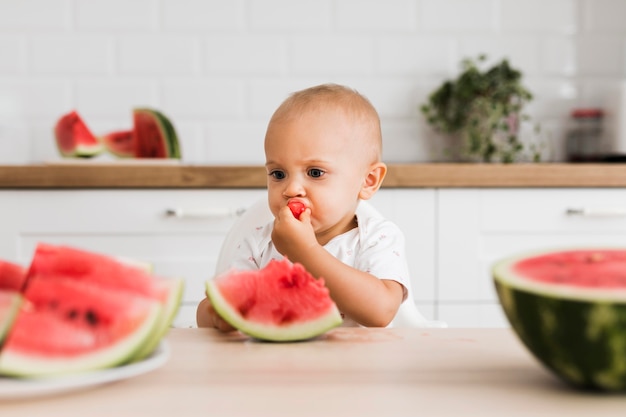 Vista frontal de um lindo bebê comendo melancia