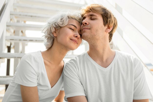 Vista frontal de um lindo casal encostado um no outro ao ar livre