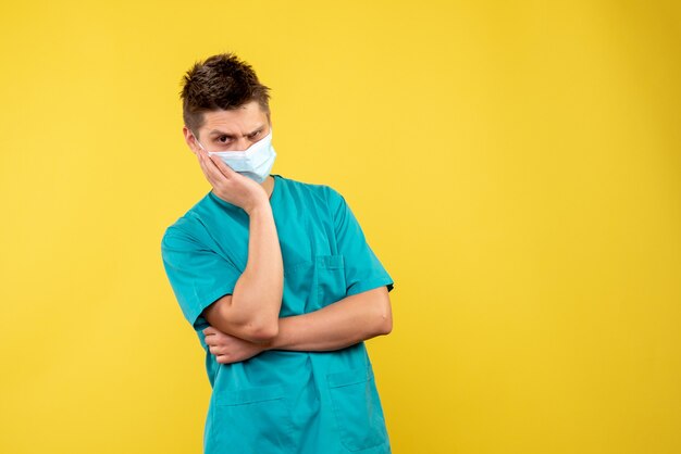 Vista frontal de um médico com máscara protetora na parede amarela