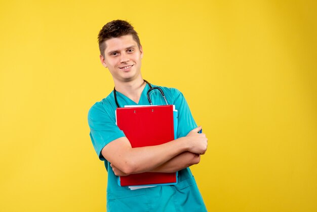 Vista frontal de um médico em terno médico com análise na parede amarela