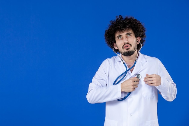 Vista frontal de um médico em terno médico com estetoscópio na superfície azul