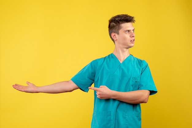 Vista frontal de um médico em um terno médico em uma parede amarela