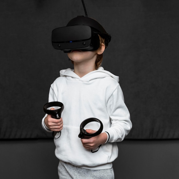Foto grátis vista frontal de um menino usando um fone de ouvido de realidade virtual