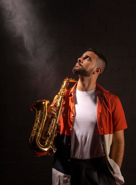 Vista frontal de um músico olhando para os holofotes enquanto segura o saxofone