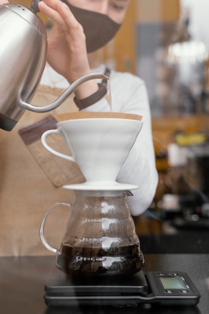 Vista frontal de uma barista coando café