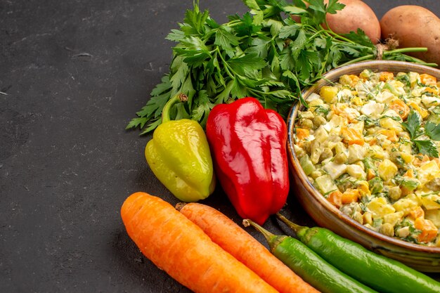 Vista frontal de uma deliciosa salada com legumes frescos em superfície escura