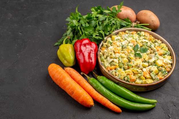 Vista frontal de uma deliciosa salada com legumes frescos em superfície escura