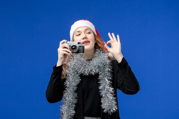 Vista frontal de uma jovem com câmera na parede azul