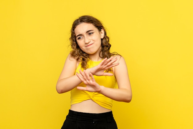 Foto grátis vista frontal de uma jovem com expressão confusa na parede amarela