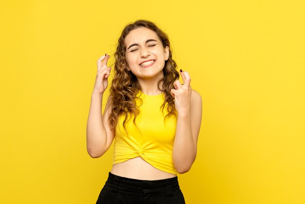 Vista frontal de uma jovem com uma expressão animada na parede amarela
