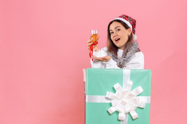 Vista frontal de uma jovem comemorando o natal com uma bebida na parede rosa