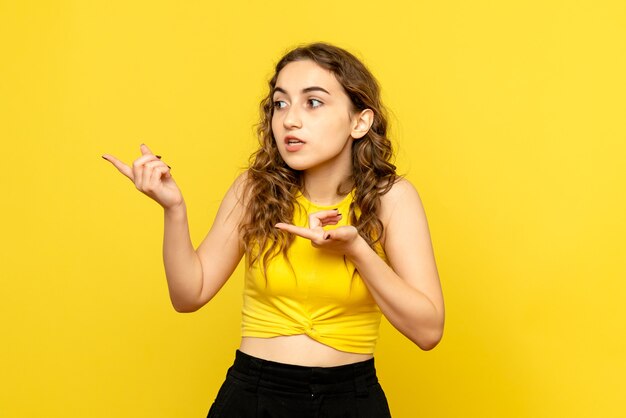 Vista frontal de uma jovem confusa na parede amarela