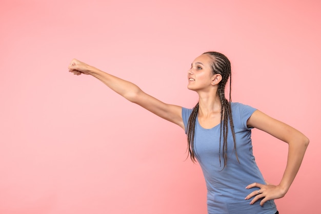 Vista frontal de uma jovem em pose de super-homem rosa