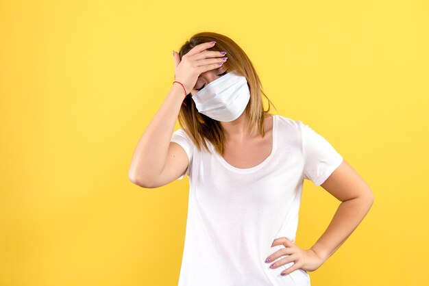 Vista frontal de uma jovem estressada na máscara na parede amarela