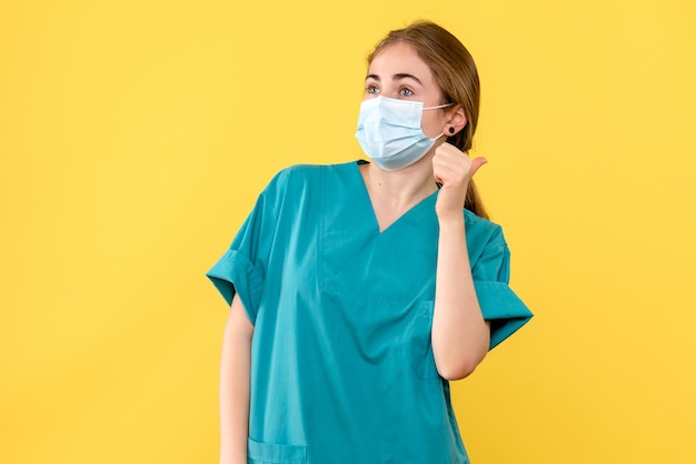 Vista frontal de uma jovem médica sobre pandemia de vírus de saúde de fundo amarelo