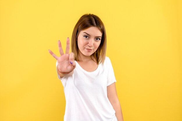 Vista frontal de uma jovem mostrando o número na parede amarela