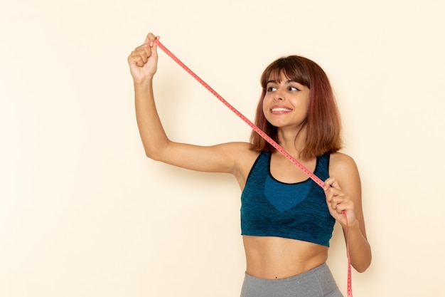 Foto grátis vista frontal de uma jovem mulher com corpo em forma em camisa azul na mesa branca clara esporte saúde menina atleta exercícios exercícios