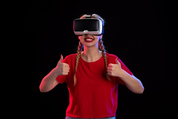 Vista frontal de uma jovem mulher jogando realidade virtual na parede escura