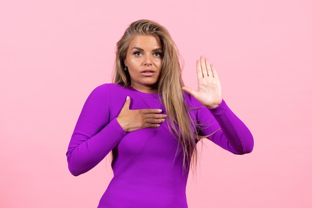 Vista frontal de uma jovem posando com um lindo vestido roxo no chão rosa moda cor beleza modelo mulher