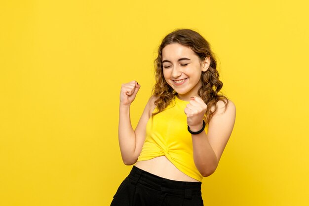 Vista frontal de uma jovem repousando em uma parede amarela