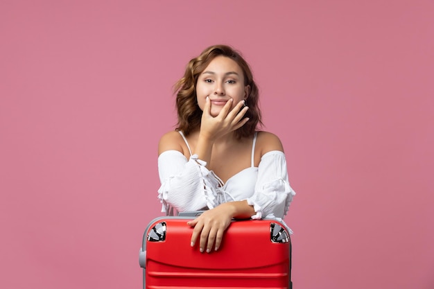 Vista frontal de uma jovem se preparando para as férias com sua bolsa vermelha na parede rosa claro