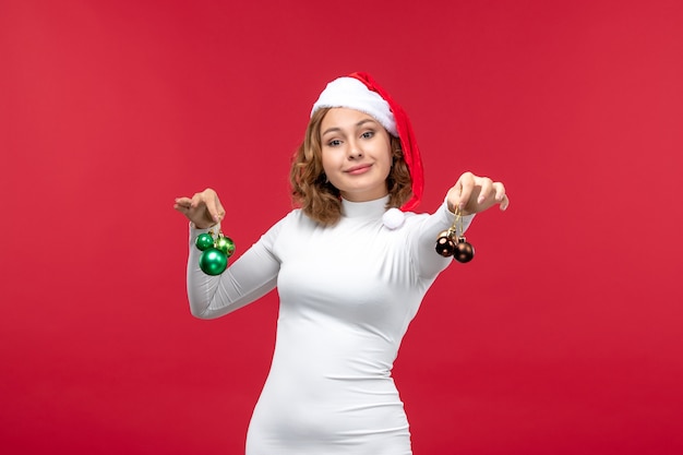 Vista frontal de uma jovem segurando brinquedos de Natal em vermelho claro