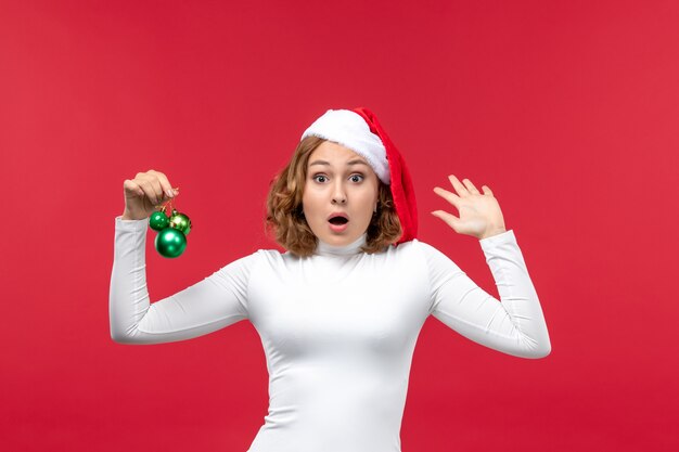 Foto grátis vista frontal de uma jovem segurando brinquedos de natal no vermelho