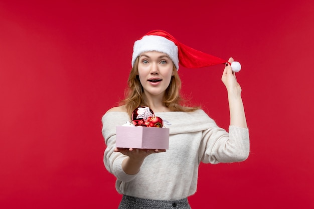 Vista frontal de uma jovem segurando brinquedos de Natal no vermelho