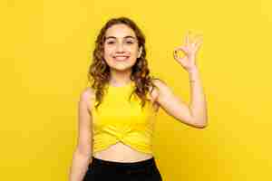 Foto grátis vista frontal de uma jovem sorrindo alegremente na parede amarela