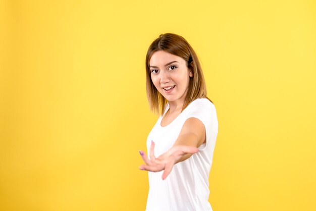 Vista frontal de uma jovem sorrindo na parede amarela