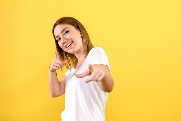 Vista frontal de uma jovem sorrindo na parede amarela