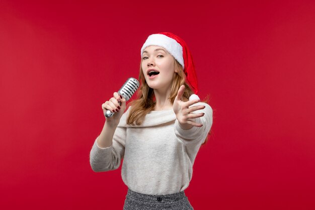 Vista frontal de uma linda mulher cantando com o microfone no vermelho