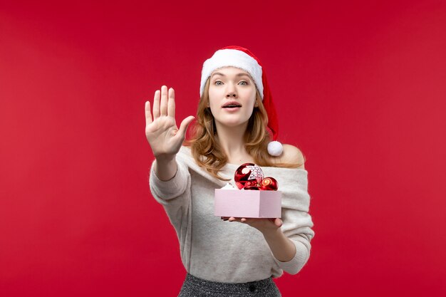 Vista frontal de uma linda mulher com brinquedos de natal em vermelho