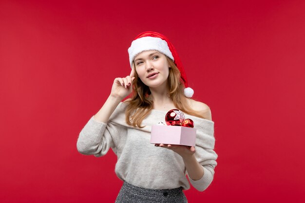 Vista frontal de uma linda mulher com brinquedos de natal em vermelho