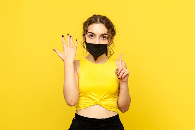 Vista frontal de uma linda mulher com máscara preta em amarelo