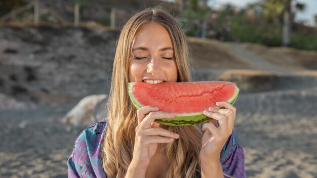 Vista frontal de uma linda mulher comendo melancia