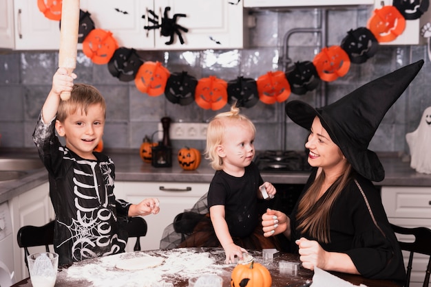 Vista frontal de uma mãe e seus filhos fazendo biscoitos de halloween