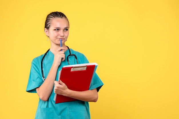 Foto grátis vista frontal de uma médica em um terno médico com diferentes análises na parede amarela