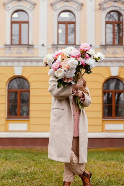 Foto grátis vista frontal de uma mulher elegante segurando um buquê de flores ao ar livre na primavera