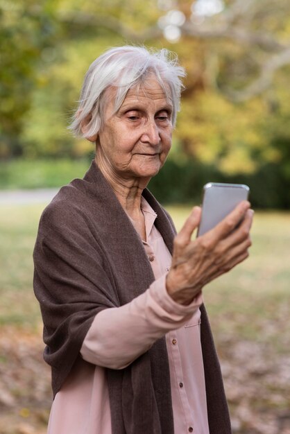 Vista frontal de uma mulher mais velha segurando um smartphone