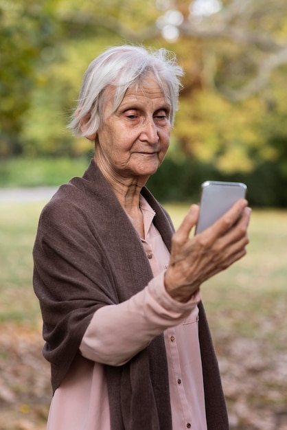 Vista frontal de uma mulher mais velha segurando um smartphone