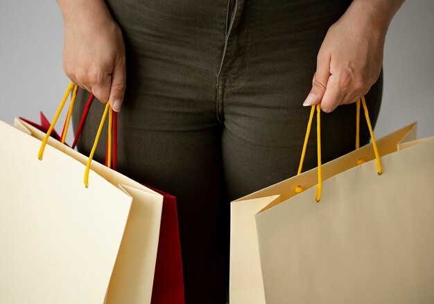 Vista frontal de uma mulher segurando muitas sacolas de compras com as duas mãos