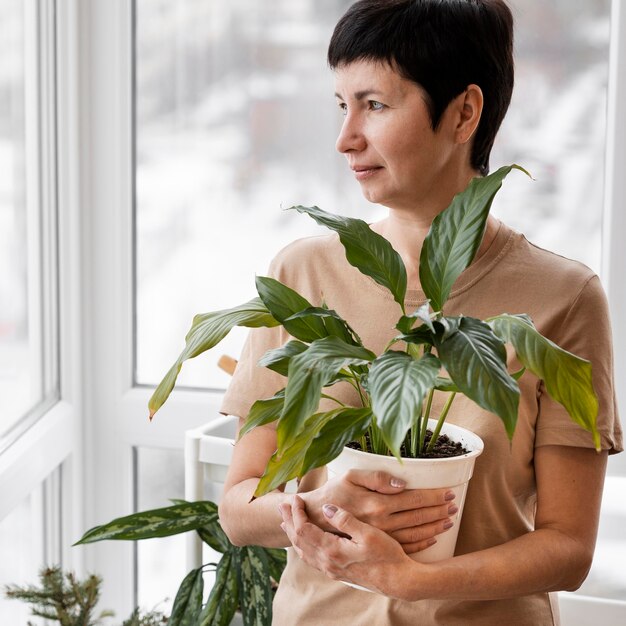 Vista frontal de uma mulher segurando um vaso de planta