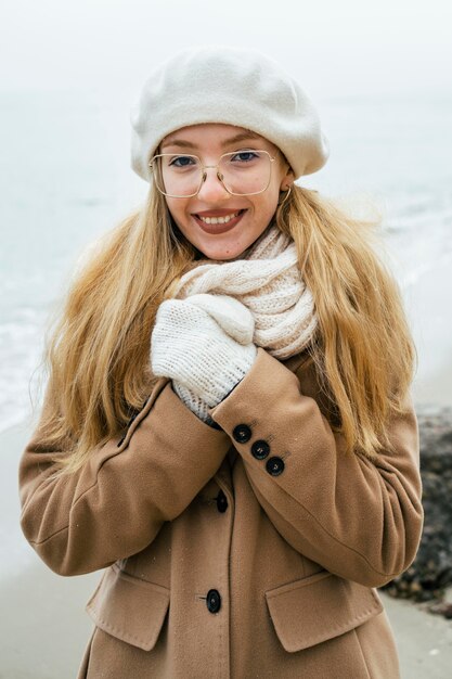 Vista frontal de uma mulher sorridente ao ar livre na praia no inverno