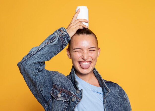 Vista frontal de uma mulher sorridente com uma lata de refrigerante na cabeça