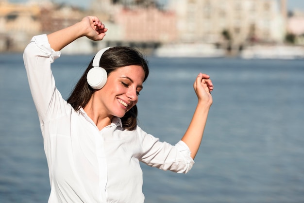 Vista frontal de uma mulher sorridente ouvindo música em fones de ouvido na praia